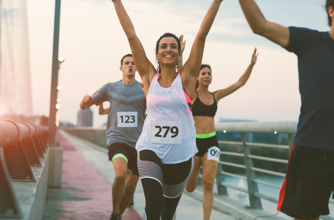 Ragazza (runner) che corre con le mani in alto per la felicità perchè ha vinto una gara