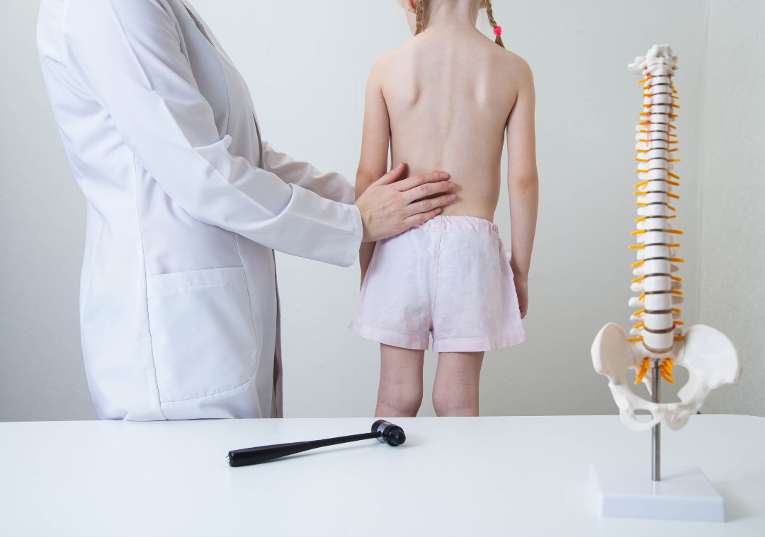 dottore con bambina che controlla colonna vertebrale