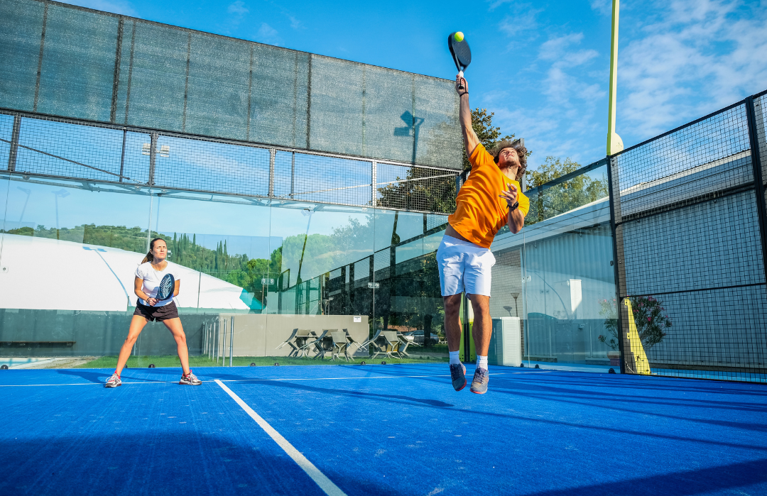 Un ragazzo e una ragazza che giocano a padel su un campo, frontali