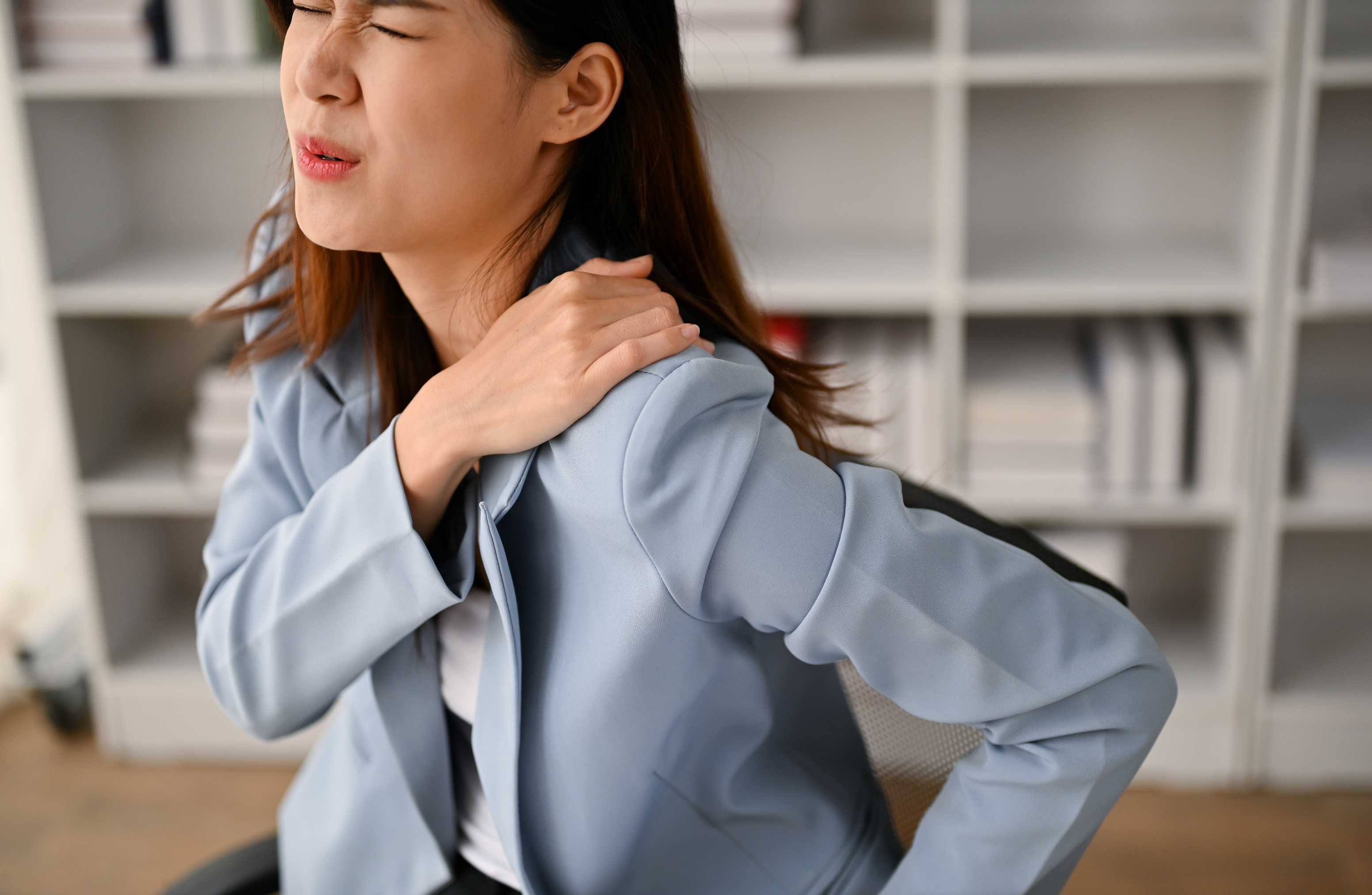 dolore alla spalla, ragazza si tocca la spalla per dolore