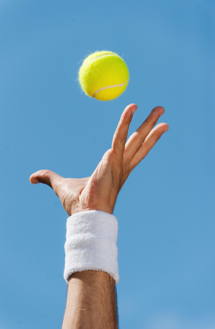 Mano lancia in aria una pallina da tennis