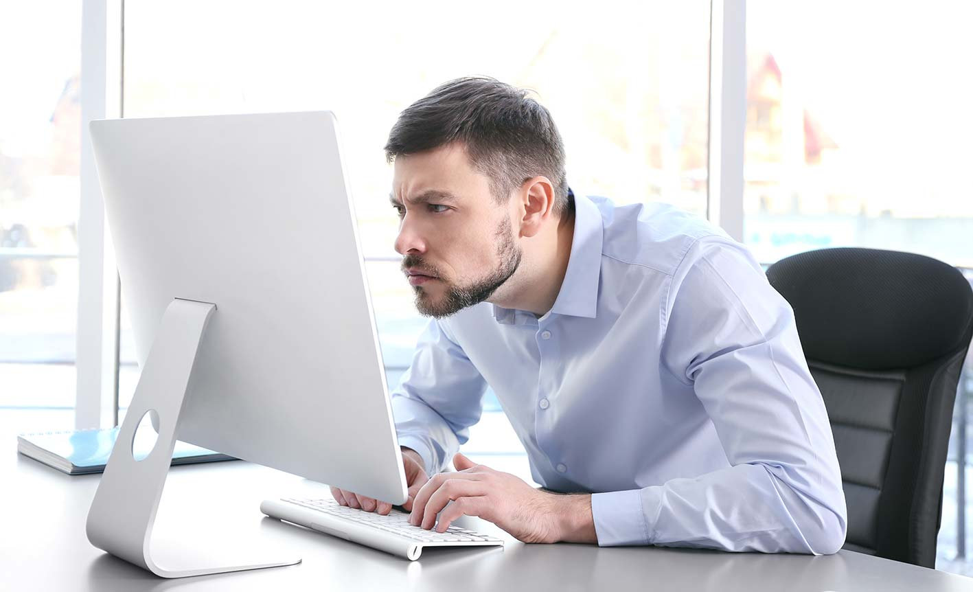 uomo alla scrivania davanti ad un computer in posizione scorretta per la schiena